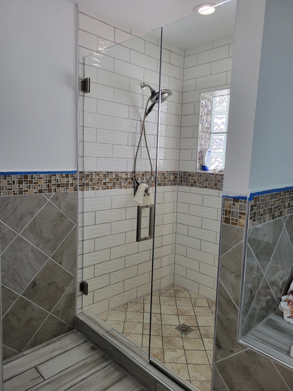 Frameless shower door and panel with brushed nickel hinges, channel and square-square handle.
